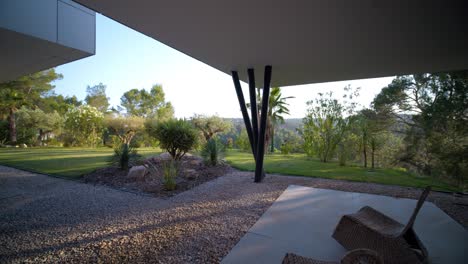 slow panning shot showing wicker seats and a beautiful garden at a villa in france