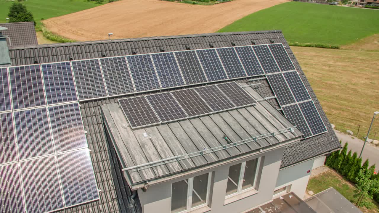 화창한 날 교외에 태양 전지판이 설치된 집 옥상을 보여주는 공중 패닝 샷