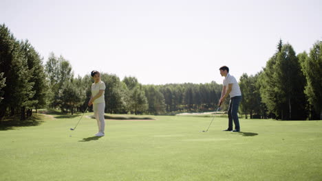 Asian-man-and-woman-playing-golf-on-a-sunny-day