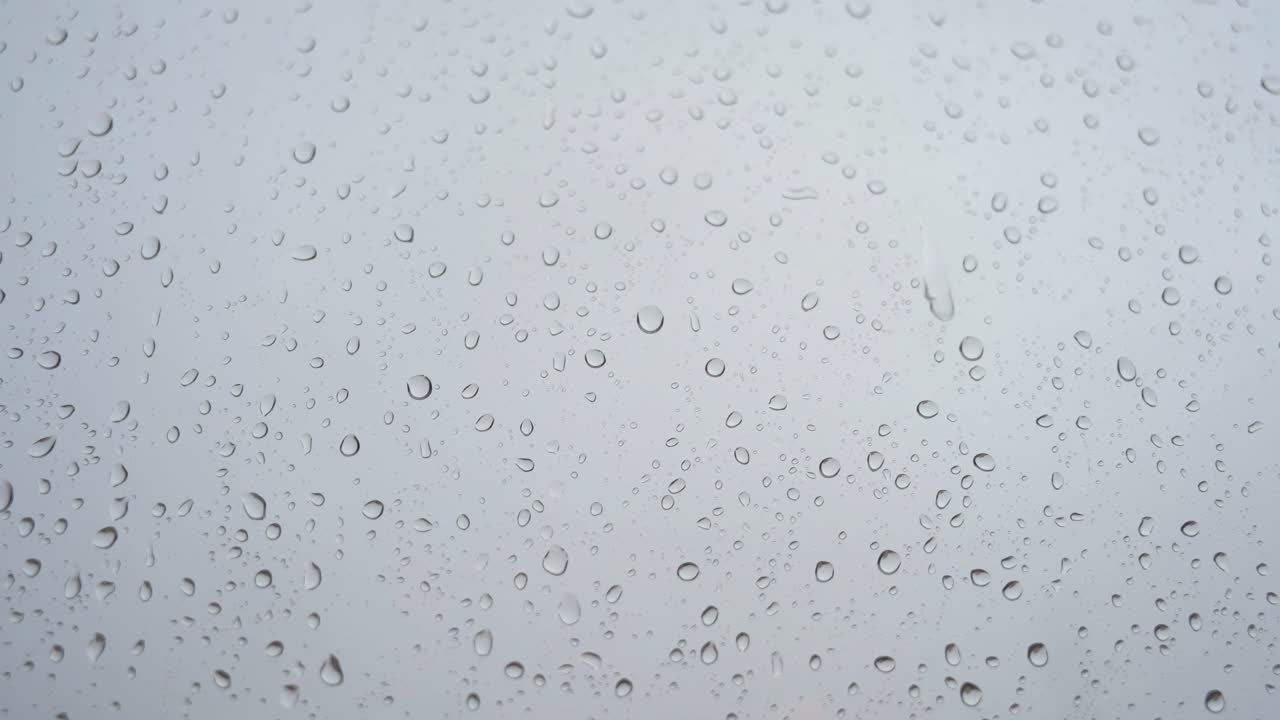 una vista cercana en cámara lenta de las fuertes gotas de lluvia se ve a través de un vidrio de la ventana