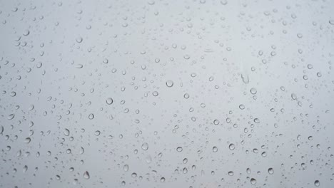 una vista cercana en cámara lenta de las fuertes gotas de lluvia se ve a través de un vidrio de la ventana