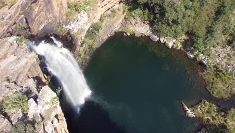 large waterfall plunging down steep rockface into a picturesque lagoon