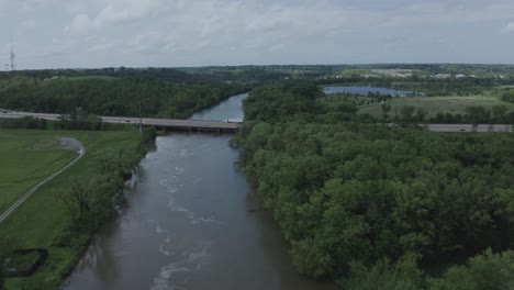 Drone-flies-over-a-river-toward-a-lone-highway-in-the-Midwestern-USA