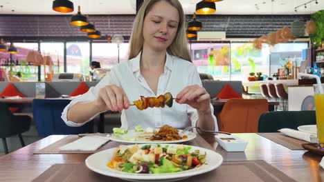 mujer comiendo pinchazos y ensalada en un restaurante