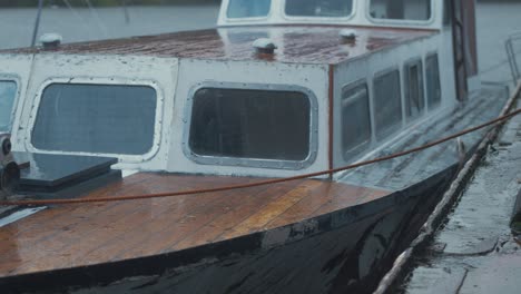 eighty year old forty foot wooden boat moored up in bleak rainy weather