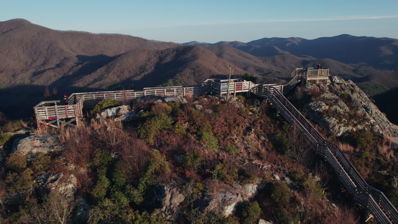 A dynamic drone shot revealing Bell Knob lookout at sunset and the staircase to the peak of the popular tourist hiking location for beautiful views of the north Georgia mountains near Hiawassee.