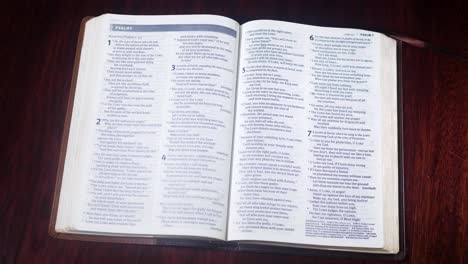 opening up a brown bible to the book of psalms on a brown table desk