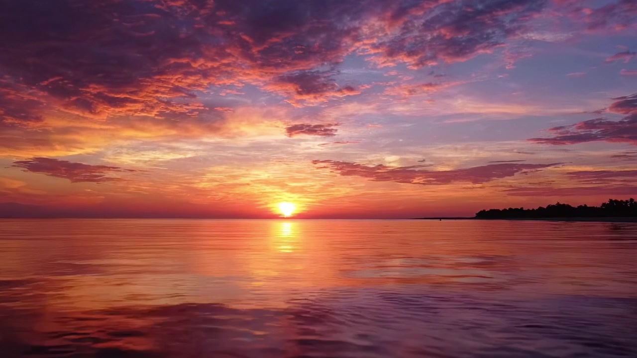 Tramonto mozzafiato su acque tranquille: uno spettacolo straordinario di colori vivaci che si riflettono sulla superficie calma, catturando la serenità e la bellezza della natura.