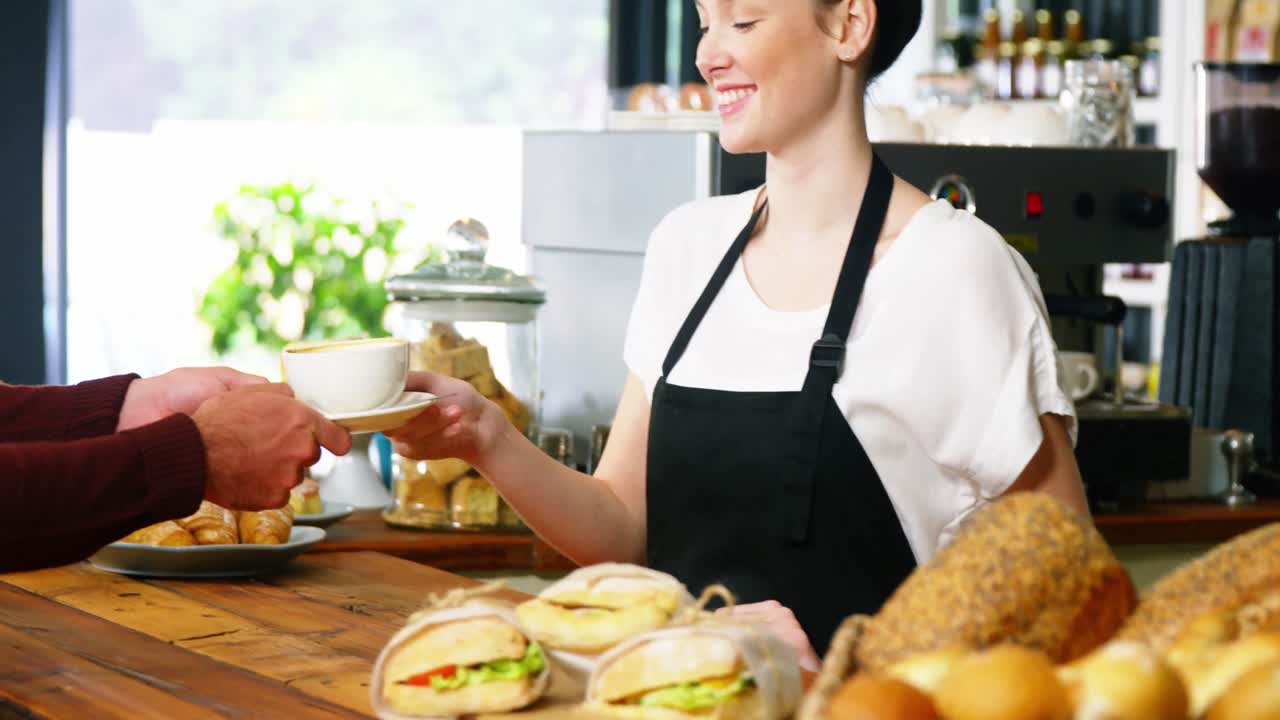 camarera sirviendo una taza de café al cliente