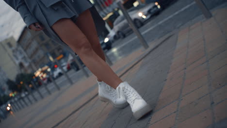 Girl-legs-walking-city-near-highway-road-with-passing-cars-at-dusk.