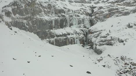 aerial of frozen mountain wall in snow covered landscape