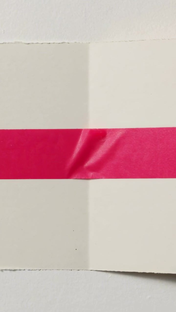 Vertical video: Camera filming cream folded paper on table while light shifting revealing red tape