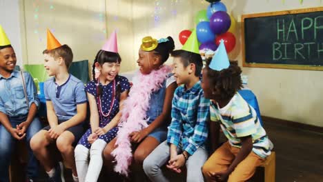 Animation-of-gold-confetti-over-diverse-happy-children-with-hats-and-balloons-having-fun-at-party