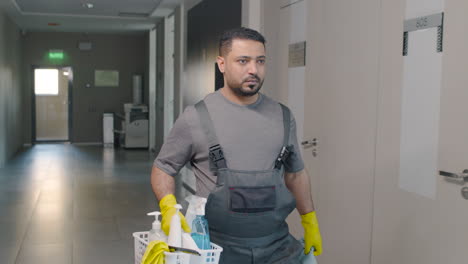 arabic cleaning man carrying cleaning products while walking inside an office building