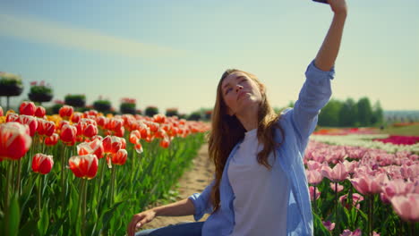 Pretty-girl-making-photo-in-outdoors.-Young-blond-woman-looking-at-camera-phone.