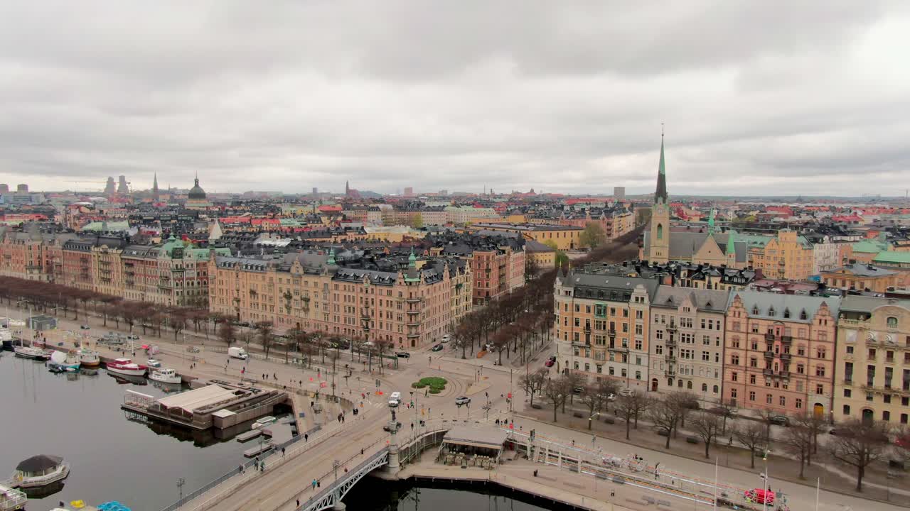 Soft descending wide aerial shot over Stockholm, revealing the city skyline beneath spring clouds