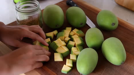 cutting green mangoes on a wooden board