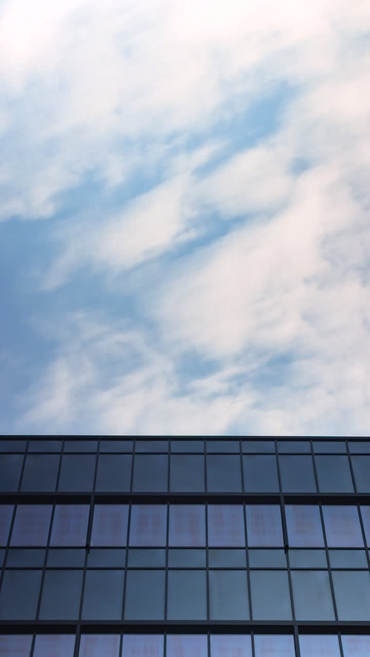 Timelapse of clouds drifting above modern glass building with large copyspace