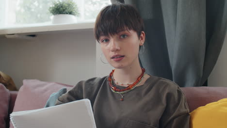 young girl taking notes during online lesson at home