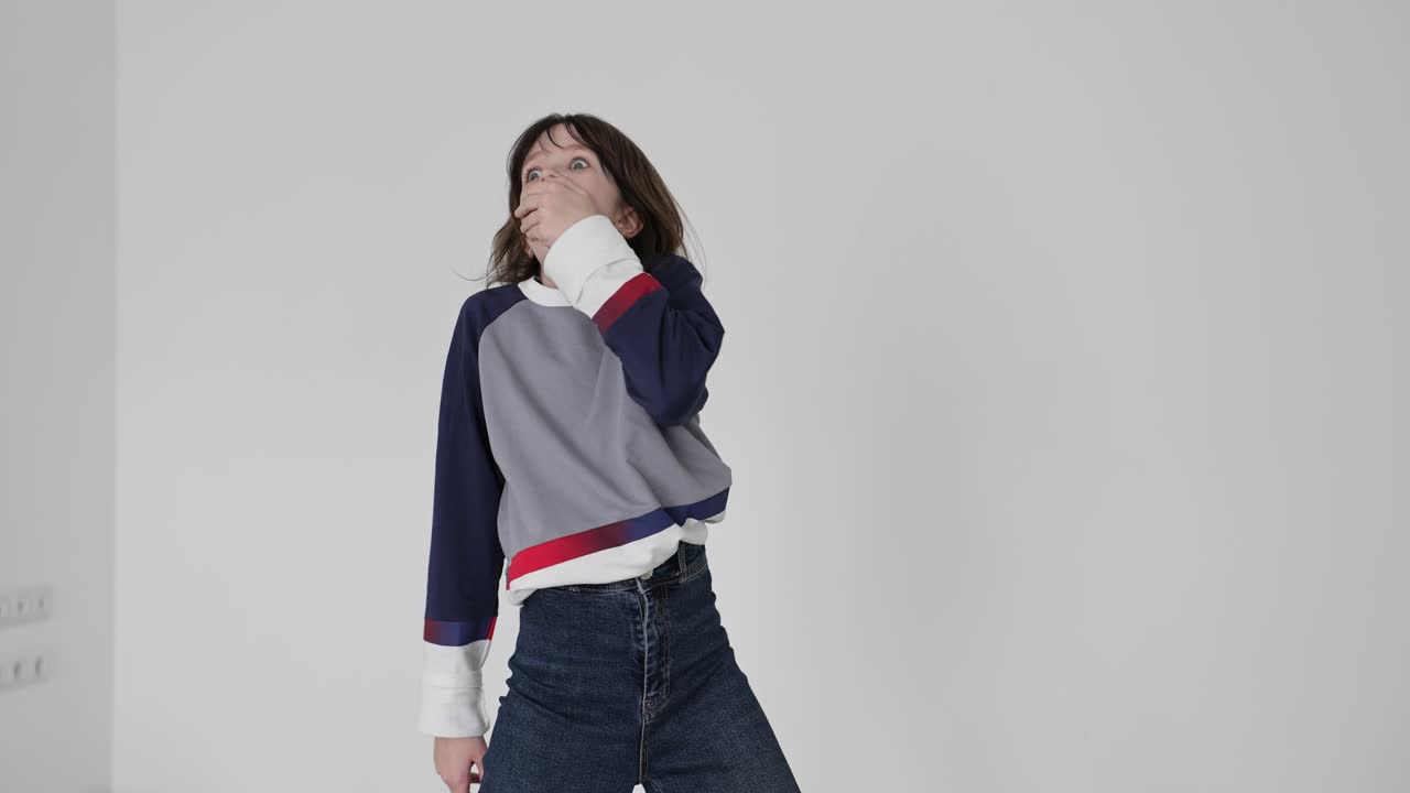 Young girl reacts with surprise or awe, covering her mouth against a white background