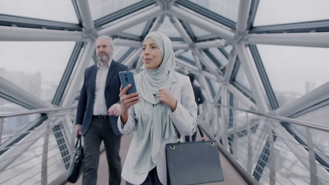 Businesswoman using smartphone on a modern city bridge