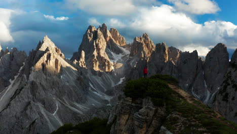 Hombre-Con-Chaqueta-Roja-Parado-En-El-Acantilado-Con-Vista-A-Los-Dolomitas