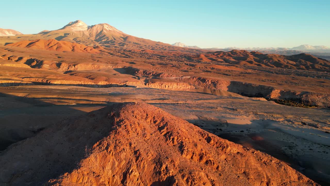 Aerial capture of barren Andes peaks glowing in soft sunset hues above the Atacama Desert
