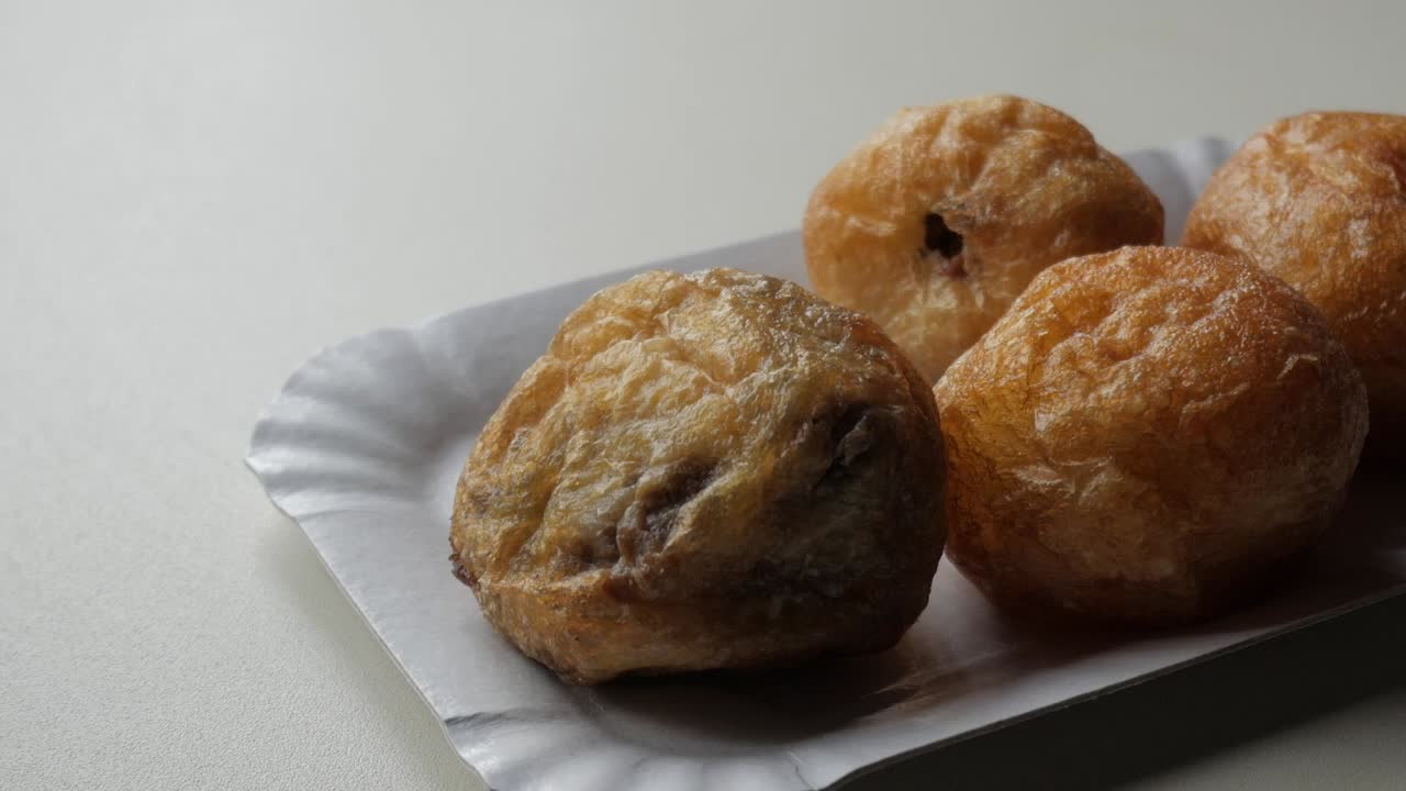 Zooming on four Buñuelos de Viento on cake paper tray.
