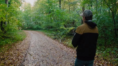 Young-Tall-Guy-Explores-The-Gyllebo-Forest-and-Rubbing-Hands-in-Excitement,-Österlen-Sweden-in-Autumn---Tracking-Medium-Shot-From-Behind