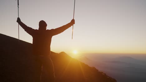 hiker on acatenango volcano raising hiking poles against sunlit background at sunrise