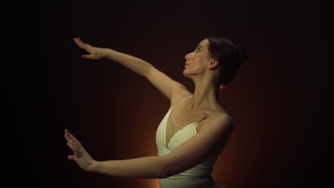 Tender dancer performing on stage. Graceful ballerina moving hands indoors.