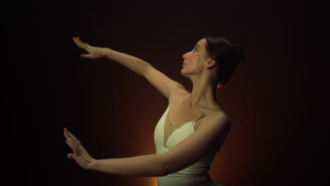 tender dancer performing on stage. graceful ballerina moving hands indoors.