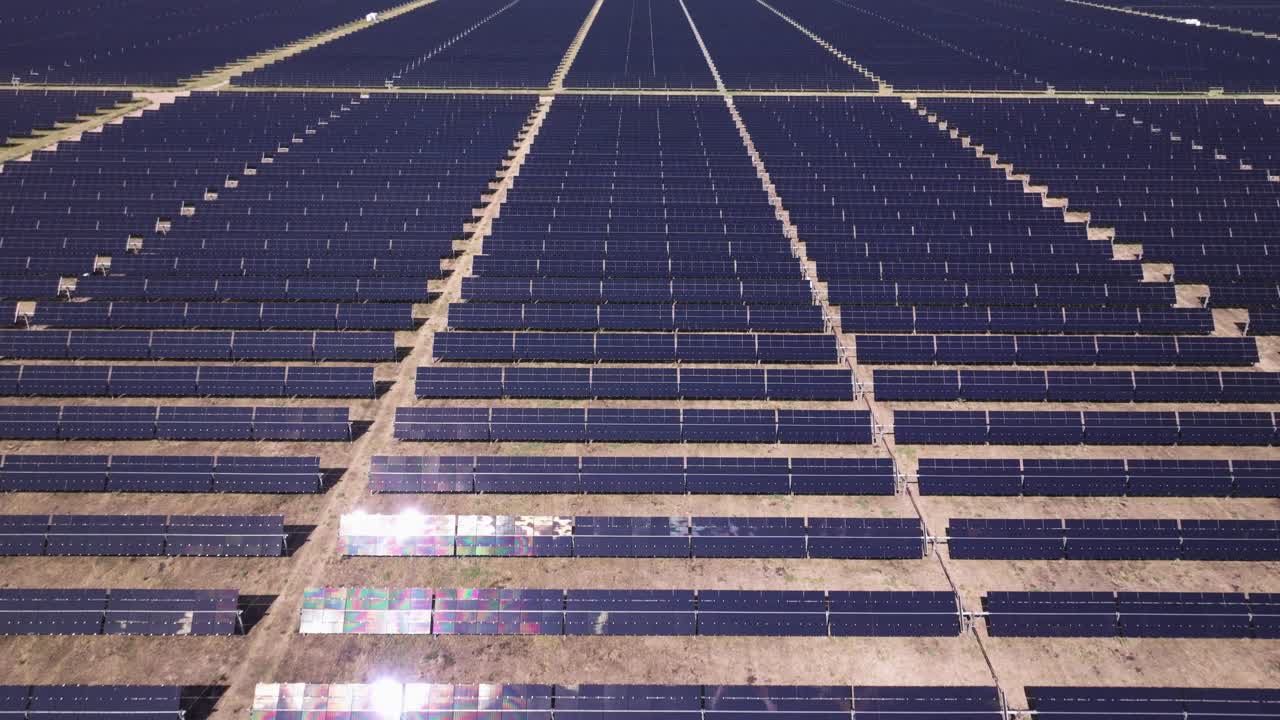 Large solar panel field stretching into the distance under bright daylight, aerial view