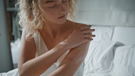 woman using moisturizing cream in morning sunlight. closeup hands rubbing lotion