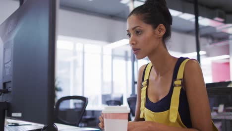 Mixed-race-businesswoman-sitting-at-desk-looking-at-computer-monitor