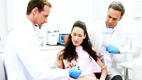 Dentist-showing-model-teeth-to-patient