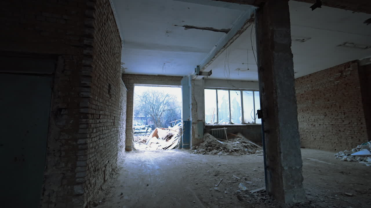 Following to large doorway in a large premise with columns. Piles of debris are inside the room.