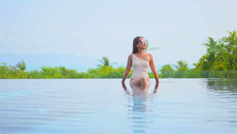 Beautiful-Asian-woman-sitting-in-infinity-pool-water-with-sexy-swimsuit