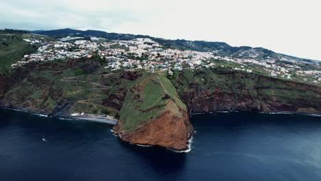 establishing aerial dolly view across ponta du garajau green island coastline, madeira, portugal