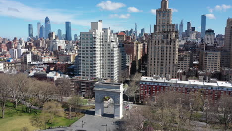 an aerial view over washington square park in nyc. the drone camera dollys in - descends towards the washington square arch. it lines up to look straight up fifth avenue - there is no traffic.