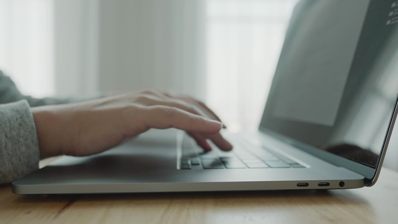 Hand of man typing on laptop notebook keyboard sit at home office desk working online. Defocused close up side view