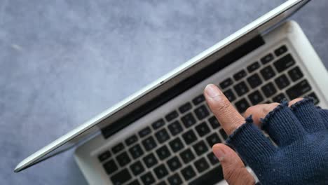 person with glove accessing laptop