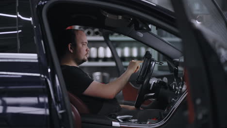 male mechanic uses a tablet computer with an augmented reality diagnostics software. specialist inspecting the car in order to find broken components inside. male uses laptop for diagnostics vehicle