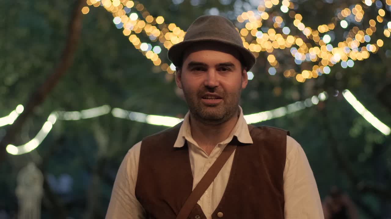 retrato de un elegante y guapo hombre con un sombrero contra un fondo de bombillas brillantes
