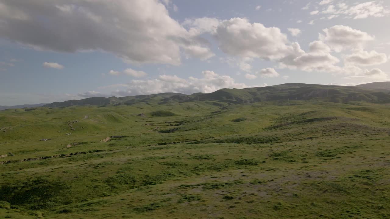 드론은 섬세하게 상승하고 활기찬 일몰 아래 녹색 언덕 위로 미끄러지며  ⁇ 락 효과를 보여줍니다.