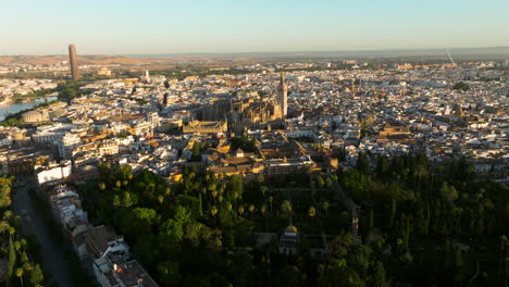 Flying-Above-The-Royal-Alcazar-Of-Seville-With-View-Of-Catedral-de-Sevilla-On-A-Sunny-Morning-In-Sevilla,-Spain