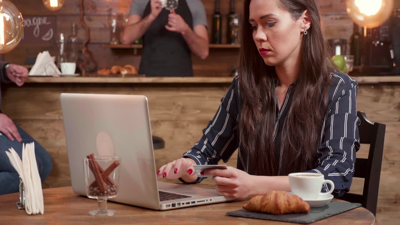 Donna che usa un laptop con una carta di credito al bar