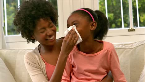 mother helping daughter blowing her nose