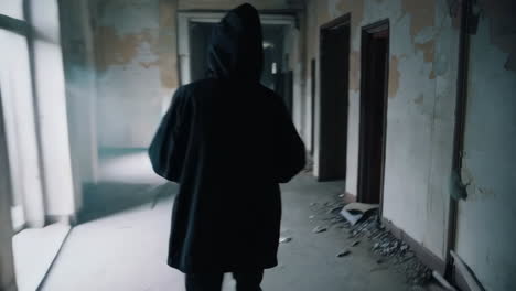 person walking down a dark abandoned hallway