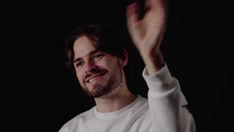 Trendy-Young-Man-waving-towards-camera,-welcoming-gesture,-close,-black-background